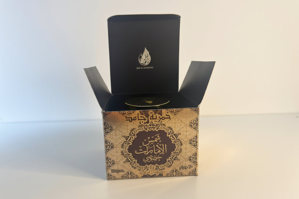 Decorative box with intricate design and a black lid featuring an emblem on a white background